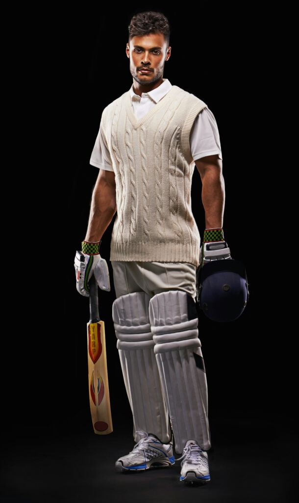 A cropped shot of an ethnic young man in cricket attire isolated on black