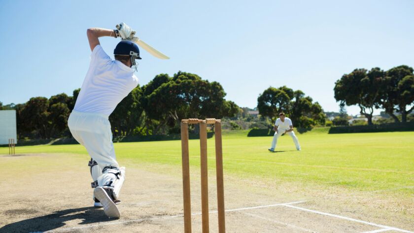 Rear view of player batting while playing cricket on field