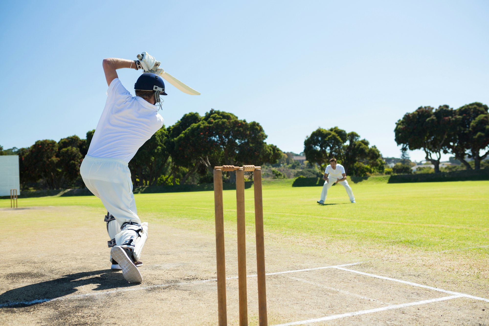 Rear view of player batting while playing cricket on field